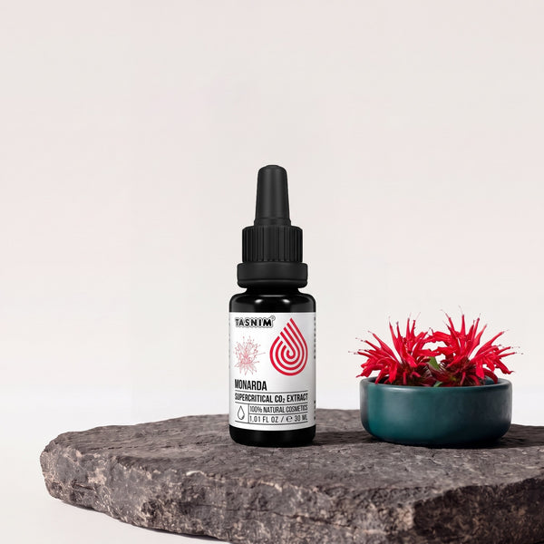 Tasnim Monarda Supercritical CO2 Extract, 30-ml-Pipettenflasche auf Basaltplatte, daneben eine Petrol-Schale mit roten Goldmelissen-Blüten