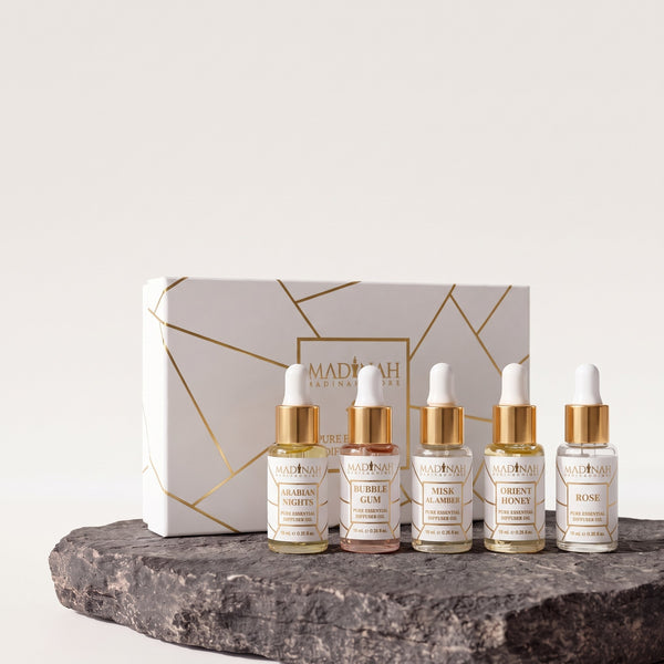 Duftöl 5er Set NR. 1: weiße Geschenkbox mit Goldlinien und fünf 10-ml-Pipettenfläschchen (Arabian Nights, Bubble Gum, Misk Al Amber, Orient Honey, Rose) auf dunkler Steinplatte