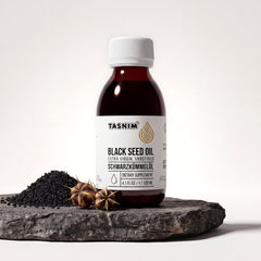 Tasnim Äthiopisches Schwarzkümmelöl, Flasche auf Basaltplatte mit Petrol-Schale voller Schwarzkümmelsamen