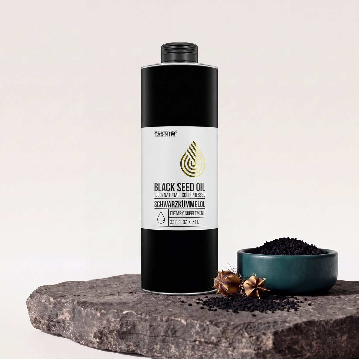 Tasnim Äthiopisches Schwarzkümmelöl 1 Liter, schwarze Dose auf Basaltplatte, daneben eine Petrol-Schale mit Schwarzkümmelsamen und eine getrocknete Nigella-Kapsel