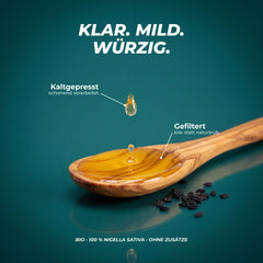 Klar, mild, würzig: gefiltertes, klares Schwarzkümmelöl tropft auf einen Holzlöffel