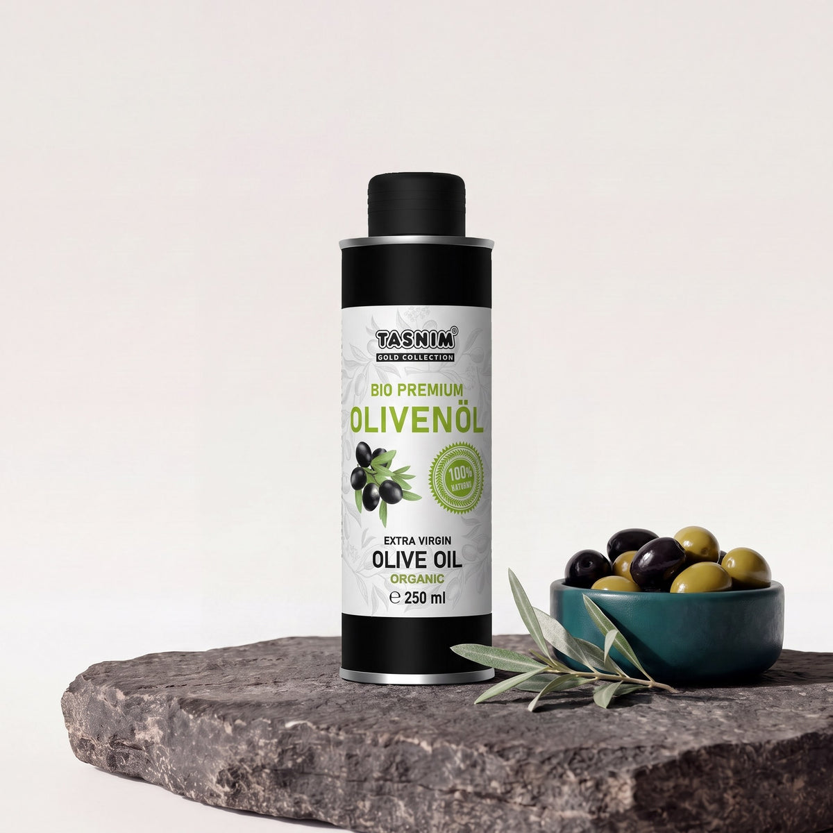 Tasnim Olivenöl Extra Virgin, 250-ml-Aluminiumdose auf Basaltplatte, daneben eine Petrol-Schale mit schwarzen und grünen Oliven und ein Olivenzweig