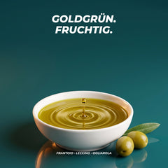 Goldgrünes Olivenöl in einer weißen Schale mit Tropfen und feinen Ringen, daneben grüne Oliven – aus den Sorten Frantoio, Leccino und Ogliarola
