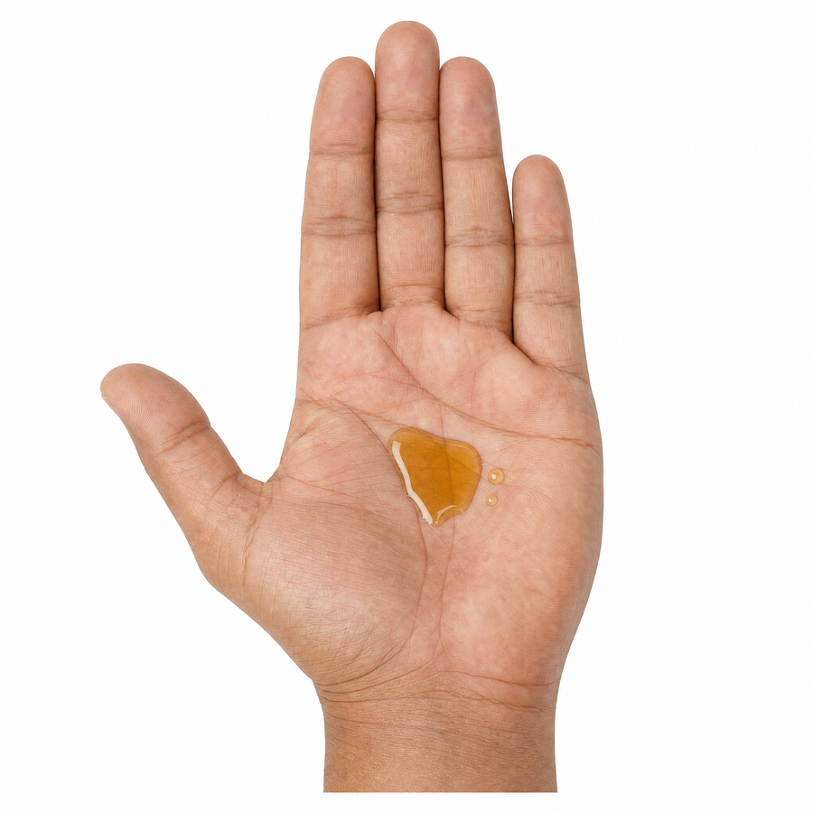 Offene Hand mit goldenem Bartöl in der Handfläche vor weißem Hintergrund