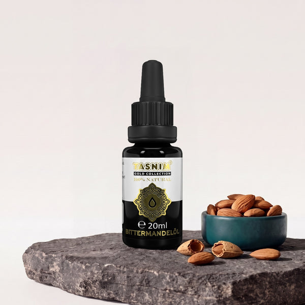 Tasnim Gold Collection Bittermandelöl 20 ml, Pipettenflasche auf Basaltplatte, daneben eine Petrol-Schale mit Mandeln