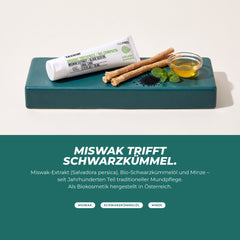 Miswak trifft Schwarzkümmel: Miswak-Stäbchen, Schwarzkümmelsamen, Minze und Öl neben der Zahnpasta-Tube