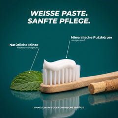Weiße Paste, sanfte Pflege: Zahnpasta-Strang auf Bambus-Zahnbürste, mineralische Putzkörper, natürliche Minze