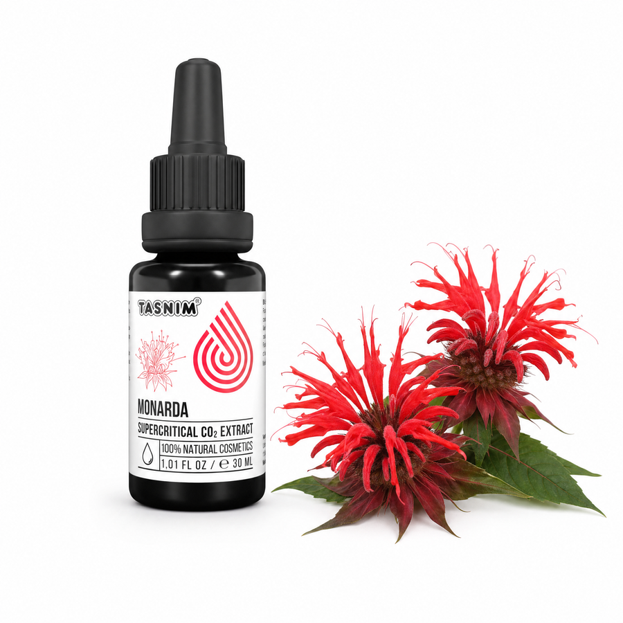 Tasnim Monardaöl 30 ml Flasche neben frischen roten Blüten der Goldmelisse (Monarda didyma)