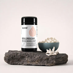Tasnim Korallencalcium, Dose mit 60 veganen Kapseln auf dunkler Steinplatte, daneben eine Petrol-Schale mit Kapseln und ein Stück Korallengestein