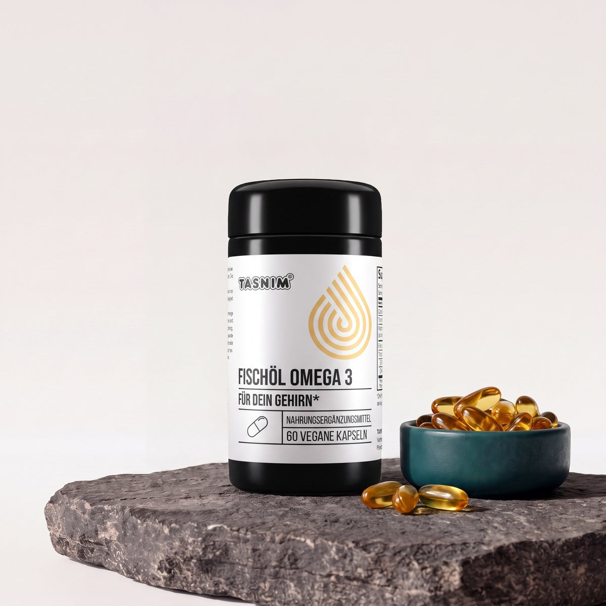 Tasnim Fischöl Omega 3, Dose mit 60 Kapseln auf Basaltplatte mit Petrol-Schale voller Omega-3-Kapseln