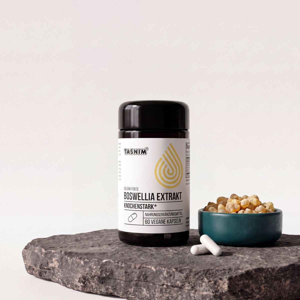 Tasnim Gelenk Forte Boswellia Extrakt, Dose mit 60 veganen Kapseln auf Basaltplatte, daneben eine Petrol-Schale mit Weihrauchharz