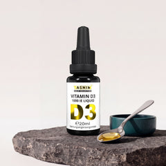 Tasnim Vitamin D3 Tropfen 1000 IE, 20-ml-Pipettenflasche auf Basaltplatte, daneben eine Petrol-Schale mit einem Löffel und einem goldenen Tropfen