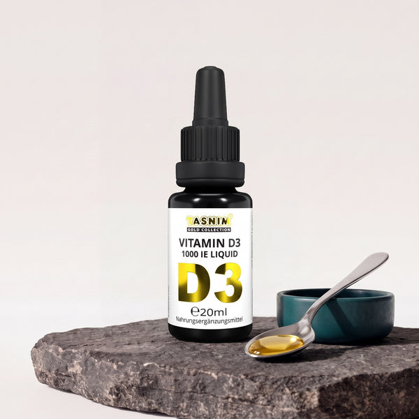 Tasnim Vitamin D3 Tropfen 1000 IE, 20-ml-Pipettenflasche auf Basaltplatte, daneben eine Petrol-Schale mit einem Löffel und einem goldenen Tropfen